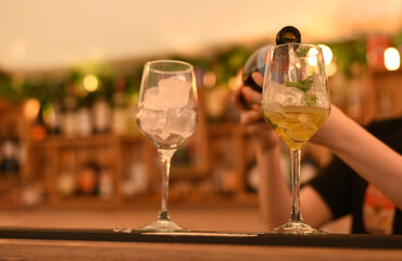 The bartender pours a cocktail into glasses