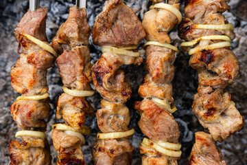 Pig shashlik with onions on a skewer. Picnic. Fried meat on fire. Background image, copy space.