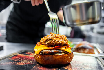 Chef adding the final touch to a gourmet burger, emphasizing the vibrant colors and textures of the...