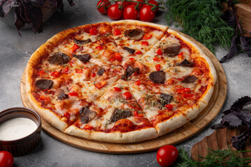 Meat pizza on a grey table.