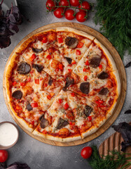 Meat pizza on a grey table.