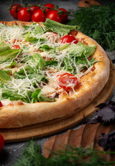 A classic caesar pizza on a grey table.