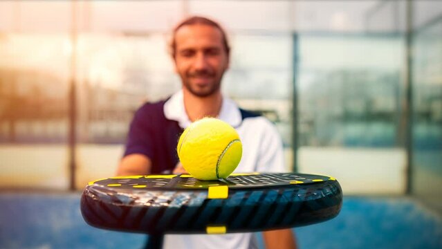 Monitor of padel holding black racket with yellow tennis ball over. Class to student on outdoor tennis court. Man paddel player playing a match in the open. Generative AI