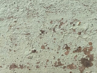 Surface of old cement plaster painted white. Closeup of grunge rough lumpy concrete texture as background. Bumpy layers of exterior stucco. Old outer wall patched finish with scratches and crevices.