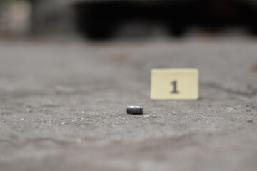 Pistol bullet shell on cement floor with blurred number one yellow paper background, concept for investigation and crime by using gun, soft focus.