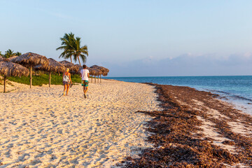 Shot of the young couple walking by the beach at the sunrise hour. Holiday