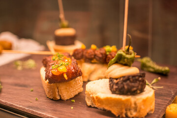 a wooden table with food on it including meat, vegetables, and cheese.