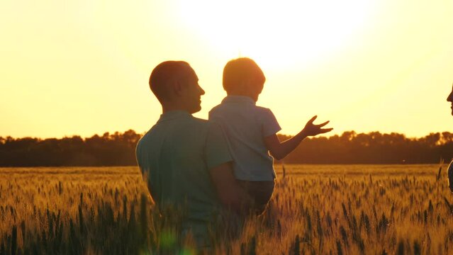 family fun outdoors. silhouette of a happy family at sunset. Dad holds a small child in his arms. the boy calls for his mom. Mom and dad kissing the baby.