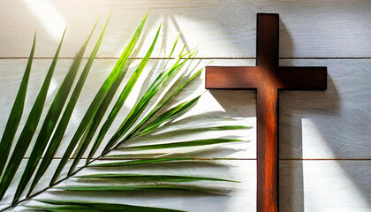 Closeup of a wooden brown religious cross and a palm branch on a white wooden background with copy space. Palm Sunday concept. Generative Ai.