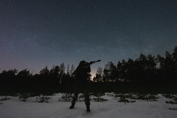A soldier with a night vision and a rifle with a silencer and laser sight against the background of...