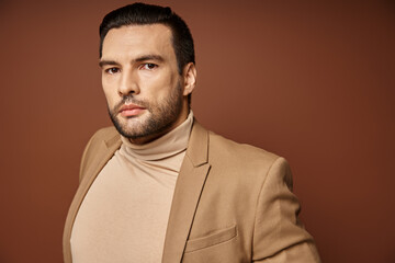 handsome man in elegant attire looking at camera on beige background, fashion-forward businessman