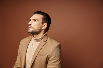 handsome man in elegant attire looking away while thinking on beige background, ideas generating