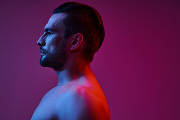 side view of seductive and muscular man with bristle posing on purple background, fashion shot
