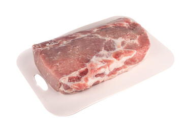A whole piece of raw pork meat on a plastic cutting board over a white background.