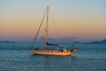 A sailboat is floating on the ocean with a beautiful sunset in the background