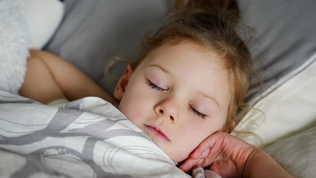 Cute little girl sleeping and grinding teeth in dreams, clenched teeth with tiredness and stress 