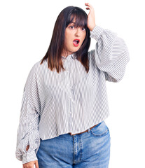 Young plus size woman wearing casual clothes surprised with hand on head for mistake, remember error. forgot, bad memory concept.