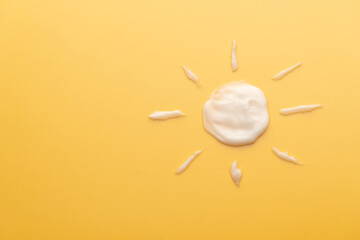 Sunscreen cream texture in sun shape on yellow background. SPF sunblock cream for protect against...