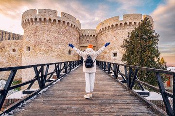 Happy tourist girl at the Zindan gate entrance to Kalemegdan fortress. Travel attractions and...