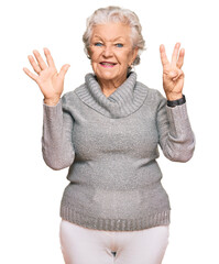 Senior grey-haired woman wearing casual winter sweater showing and pointing up with fingers number eight while smiling confident and happy.