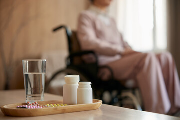Medications and recovery pills with glass of water on table for old patient - obrazy, fototapety, plakaty