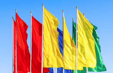 Colorful flags fluttering against a blue sky - 768041392
