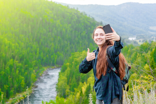 Happy woman takes a selfie on the background of mountains