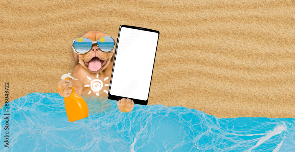 Poster Funny Mastiff puppy at beach applying suntan lotion or sun block and showing big smartphone with white blank screen in it paw. Empty space for text