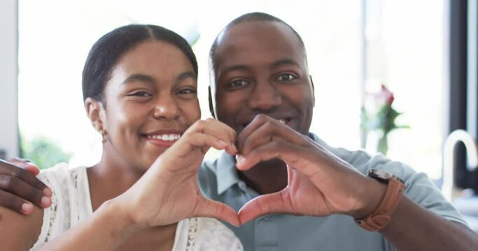 A diverse couple forms a heart shape with their hands