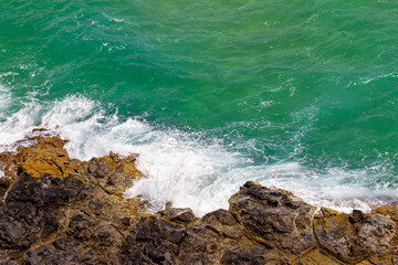 Waves Of Blue Sea Crashing On Rocks In Vietnam Coastal.