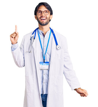 Handsome hispanic man wearing doctor uniform and stethoscope pointing finger up with successful idea. exited and happy. number one.