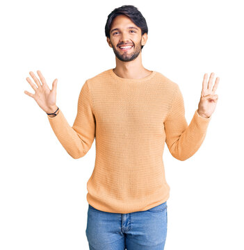Handsome hispanic man wearing casual sweater showing and pointing up with fingers number eight while smiling confident and happy.