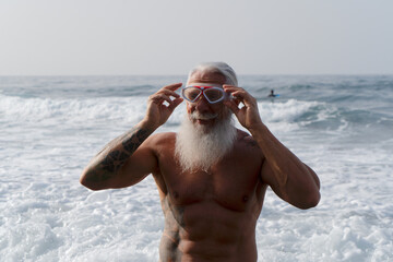 Happy fit senior man having fun buthing in the sea in the mask. Elderly healthy people lifestyle...