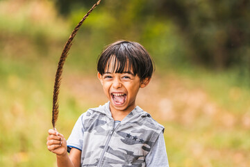 A young boy in playful exuberance, with nature as his playground. The spirit of adventure shines through his bright smile. Unbridled joy into the nature.
