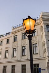 Fototapeta na wymiar Straßenlaterne leuchtet in einer Straße, Haus im Hintergrund