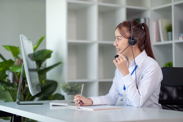 Portrait of happy smiling female customer support phone operator at workplace. Asian