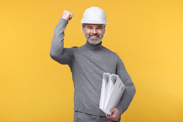 Architect in hard hat holding folders on orange background