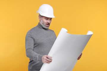 Emotional architect in hard hat holding draft on orange background