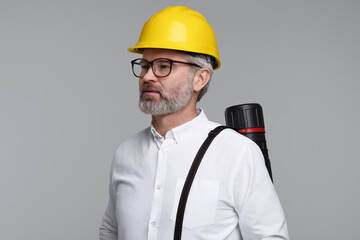 Architect in hard hat with drawing tube on grey background