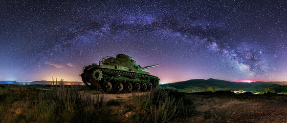 night view of a battle tank placed as a monument in the town of Quintanilla Cabe Rojas, in the Bureba region, Burgos, under a starry sky - obrazy, fototapety, plakaty