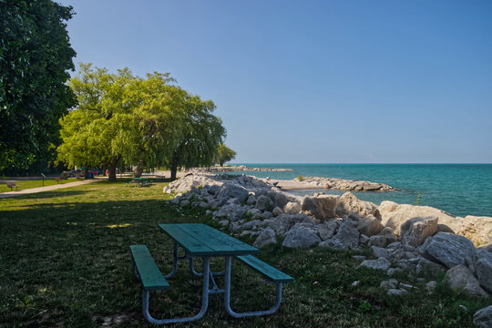 Picnic benches to enjoy the scenery of the lake and the port The beautiful Huron lake seen from the beach behind the rocks - Goderich, ON, Canada