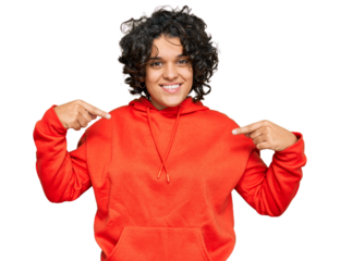 Young hispanic woman with curly hair wearing casual sweatshirt looking confident with smile on face, pointing oneself with fingers proud and happy.