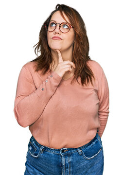 Young plus size woman wearing casual clothes and glasses thinking concentrated about doubt with finger on chin and looking up wondering
