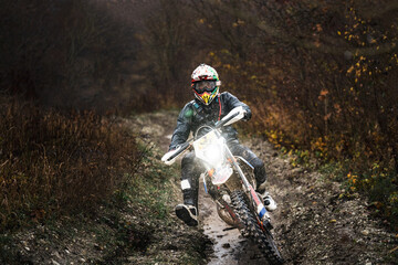 Professional motorcycle rider in sport gear take a turn in the forest, a person riding a motorbike...