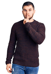 Young handsome man wearing casual sweater asking to be quiet with finger on lips. silence and secret concept.