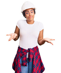 Young african american woman with braids wearing hardhat and builder clothes clueless and confused...