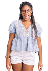 Young african american woman with braids wearing casual summer clothes and glasses winking looking...