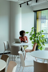 Serene Morning at a Modern Cafe, A Woman Enjoys A Warm Beverage While Working on Her Laptop