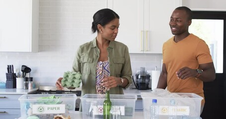 A young African American couple is engaged in recycling at home - Powered by Adobe