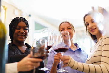 Group of diverse ethnicity people enjoy testing red wine together.